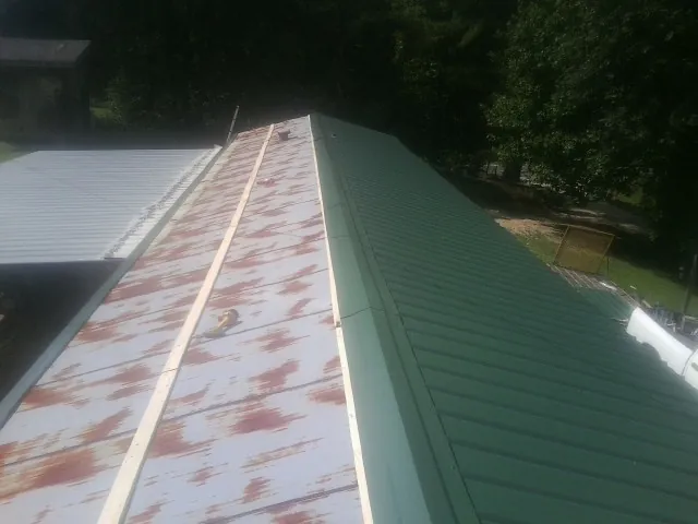 Old rusted panels beside newly installed green metal roofing — Wind Damage Roof Repair by Roofing Brothers in Cresson