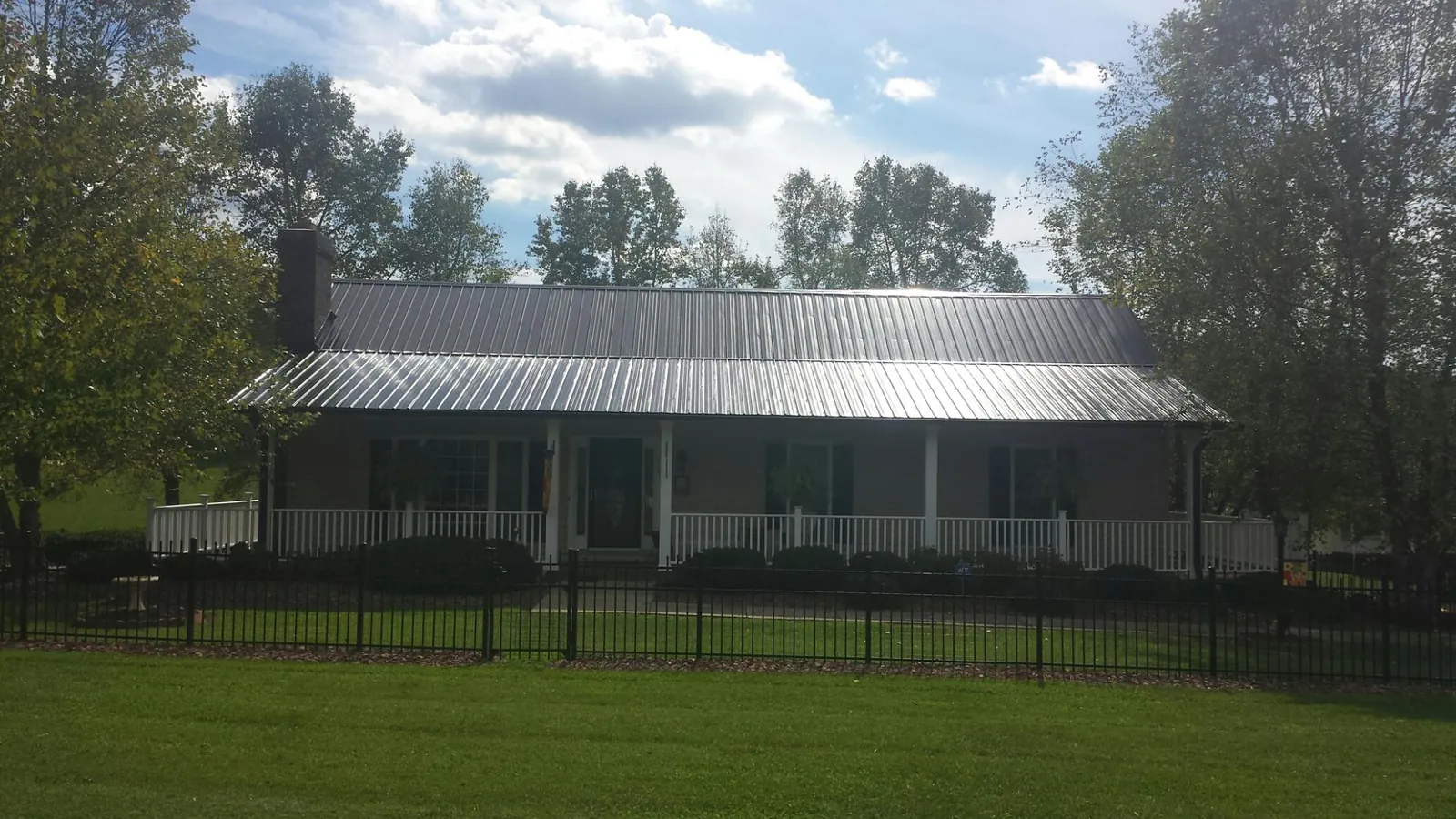 Gray metal roof on a brick ranch with a full width front porch — Gutter Guard Installation work by our crew in Cresson